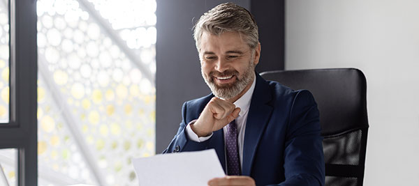 man sitting in leather chair looking at paper