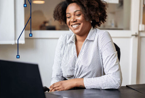 Woman in Striped Collared Shirt Smiling at Laptop on Desk