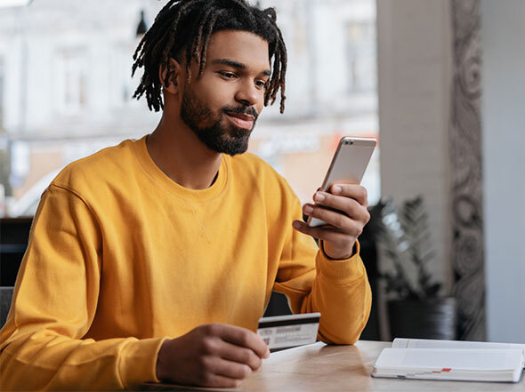 Man in Yellow Sweatshirt Using Credit Card to Transfer Money on Cell Phone