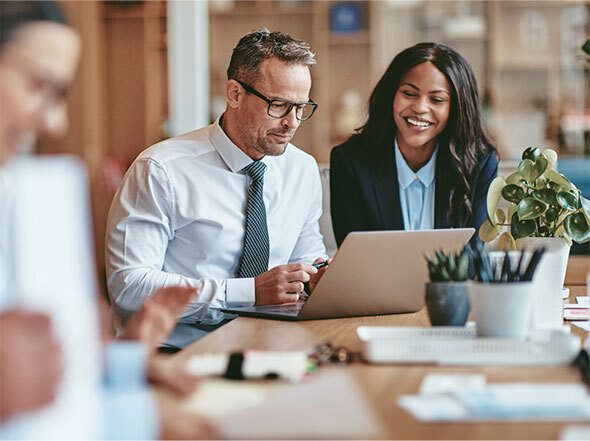 Male and Female Coworkers Wearing Business Clothes and Sitting Around Laptop