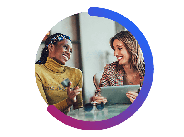 Two Women Smiling at Each Other While Holding a Tablet