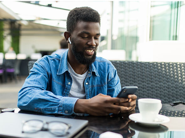 Man at cafe smiling using cell phone