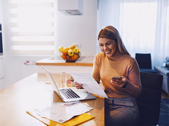 Woman smiling holding bill and cell phone