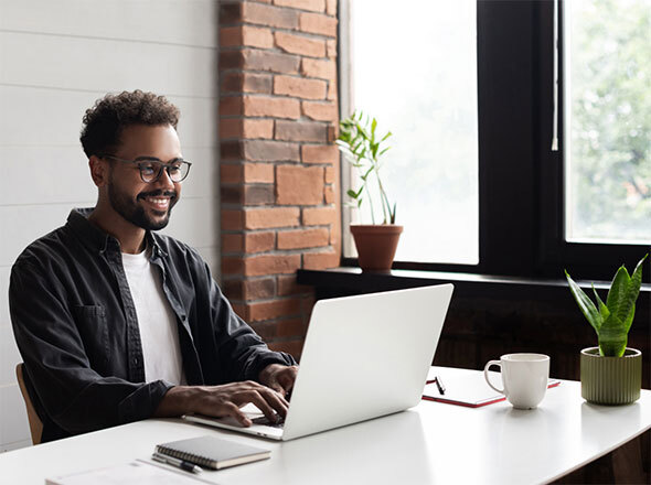 Man with glasses smiling using laptop