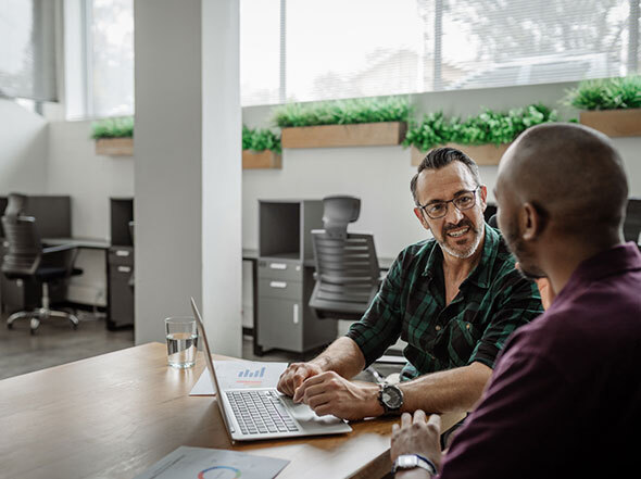 Two men talking near laptop