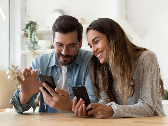 Couple Smiling While Looking at Each Other's Phone Screens