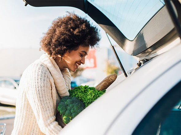 Woman Putting Groceries in Trunk of Car