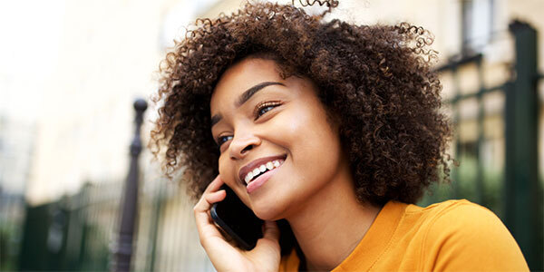Girl in Yellow Sweater Grinning While Talking on Mobile Phone
