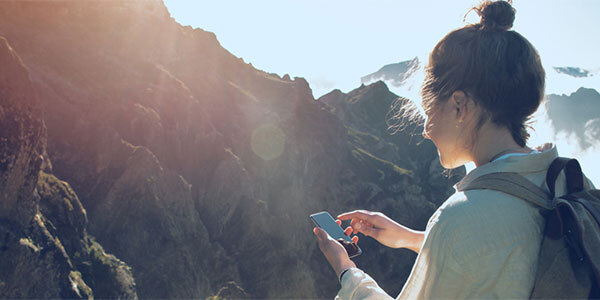 Woman Hiking While Paying Bills on Cell Phone Using Paymentus