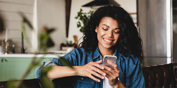Woman on Bench Smiling While Looking at Cell Phone
