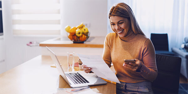Woman Smiling While Paying a Bill from her Cell Phone