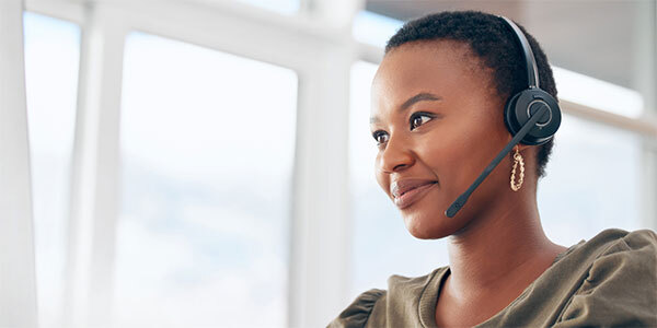 Woman in Green Sweater Working in Call Center, Wearing Headset While Smiling